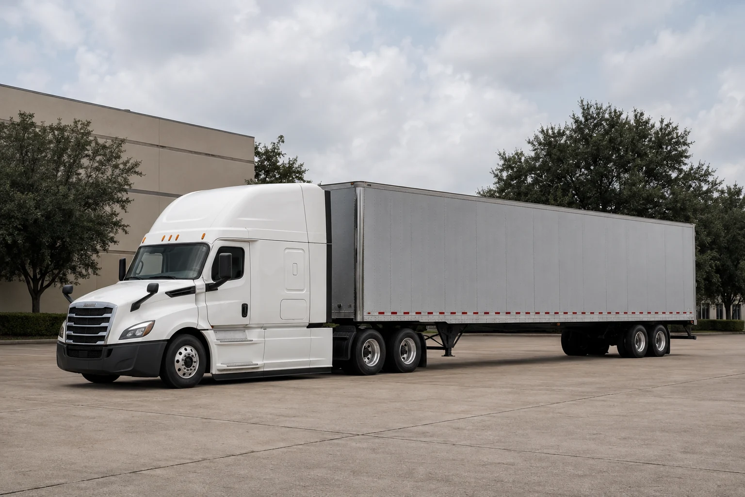 White tractor and silver trailer parked in a green Texas industrial setting
